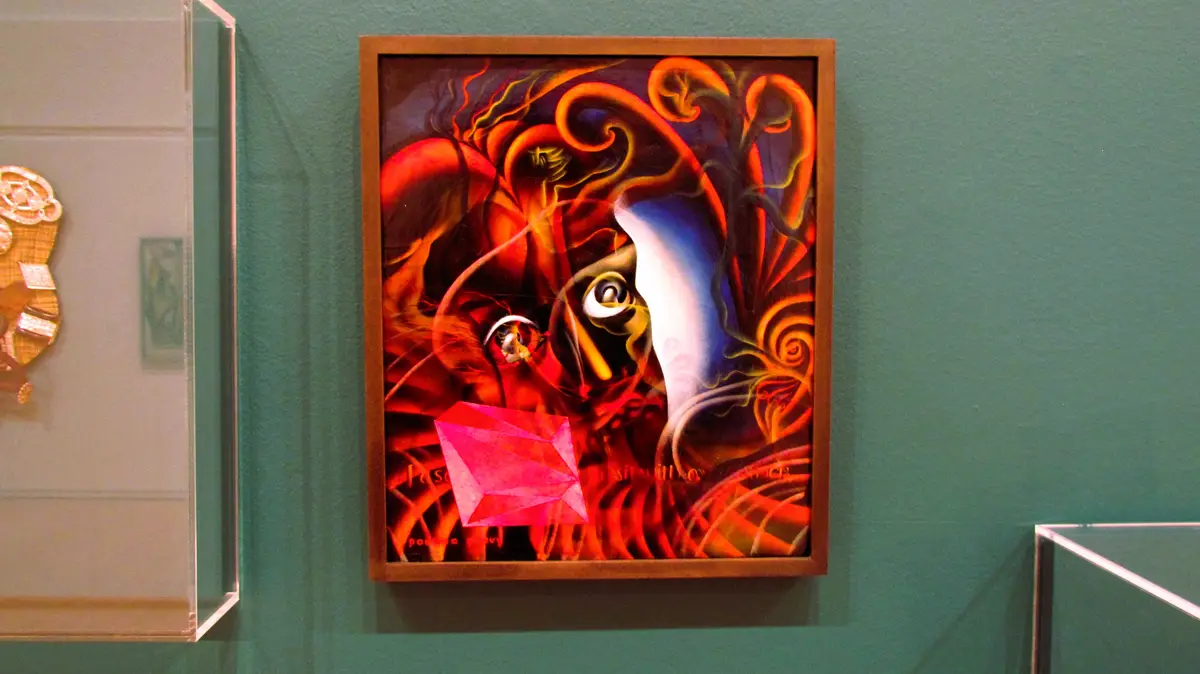 A framed abstract painting with swirling red, orange, and blue patterns, featuring two stylized eyes and a pink geometric…