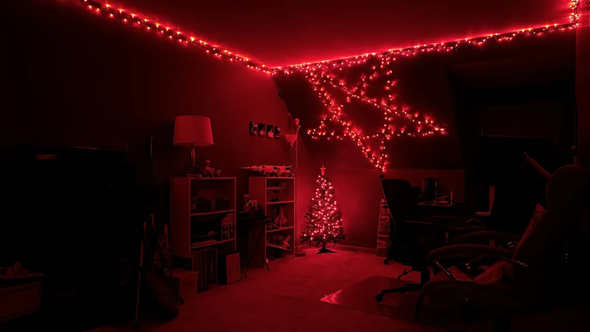 A dimly lit room bathed in red light from string lights draped along the ceiling and forming a large star shape on the wall…