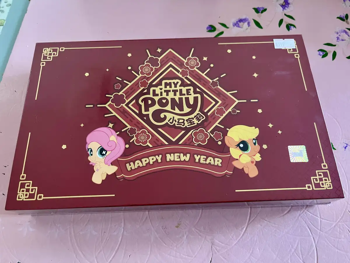 A red and gold My Little Pony New Year's themed box featuring cartoon ponies Fluttershy and Applejack, with Chinese New Year…