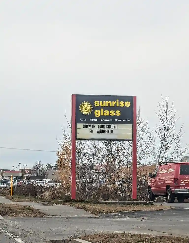 A large outdoor sign for 'sunrise glass' with services listed as Auto, Home, Showers, Commercial. The marquee below reads…