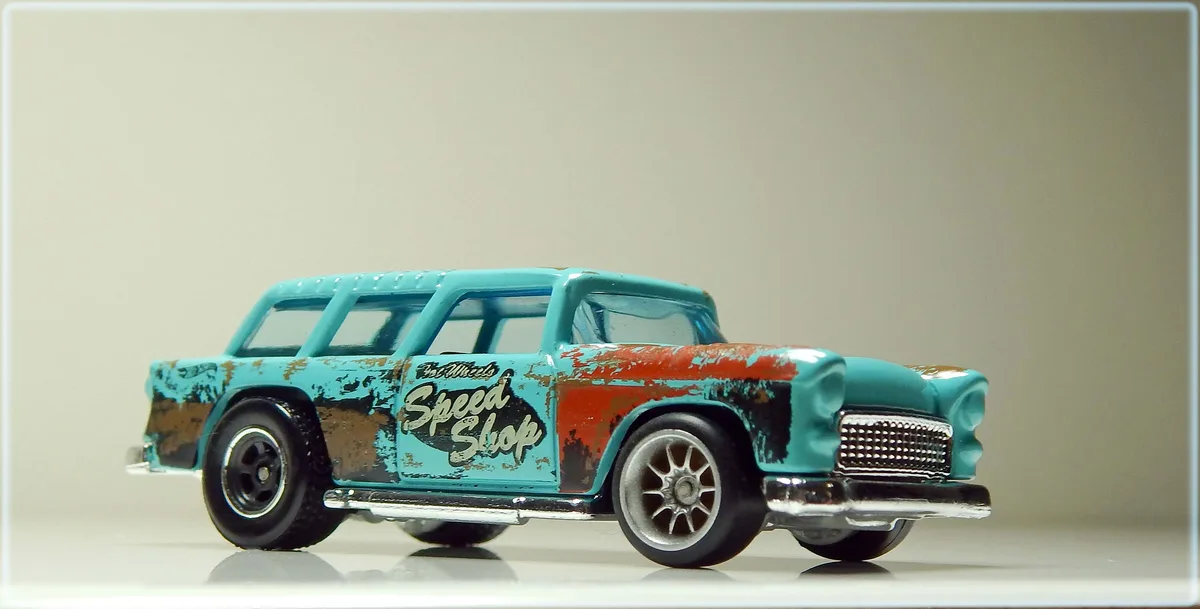 A weathered turquoise and red Hot Wheels toy car with 'Speed Shop' lettering on its side, showing intentional rust and…