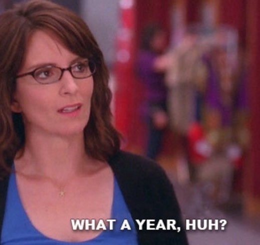 A woman with glasses and brown hair, wearing a blue top and black cardigan, looks slightly exasperated or sarcastic. The…