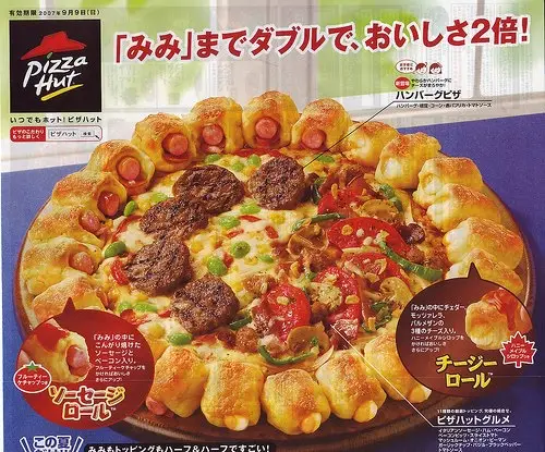 A Pizza Hut Japanese advertisement for a 'Hamburger Pizza' featuring a pizza with hamburger patties and cheese rolls shaped…