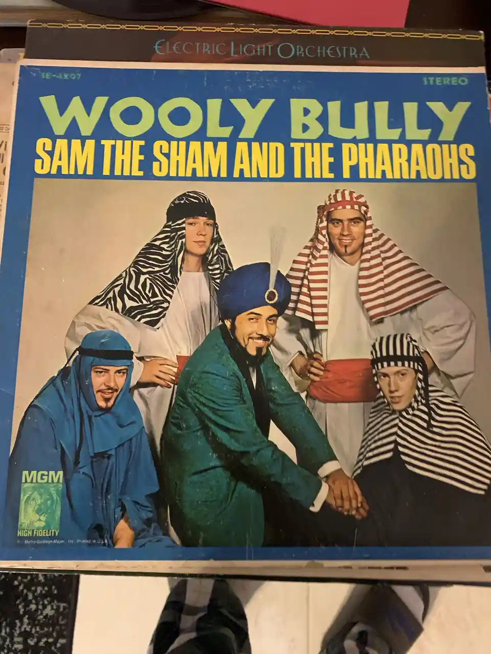 A vintage album cover for 'Wooly Bully' by Sam the Sham and the Pharaohs, showing five men in colorful, stylized…