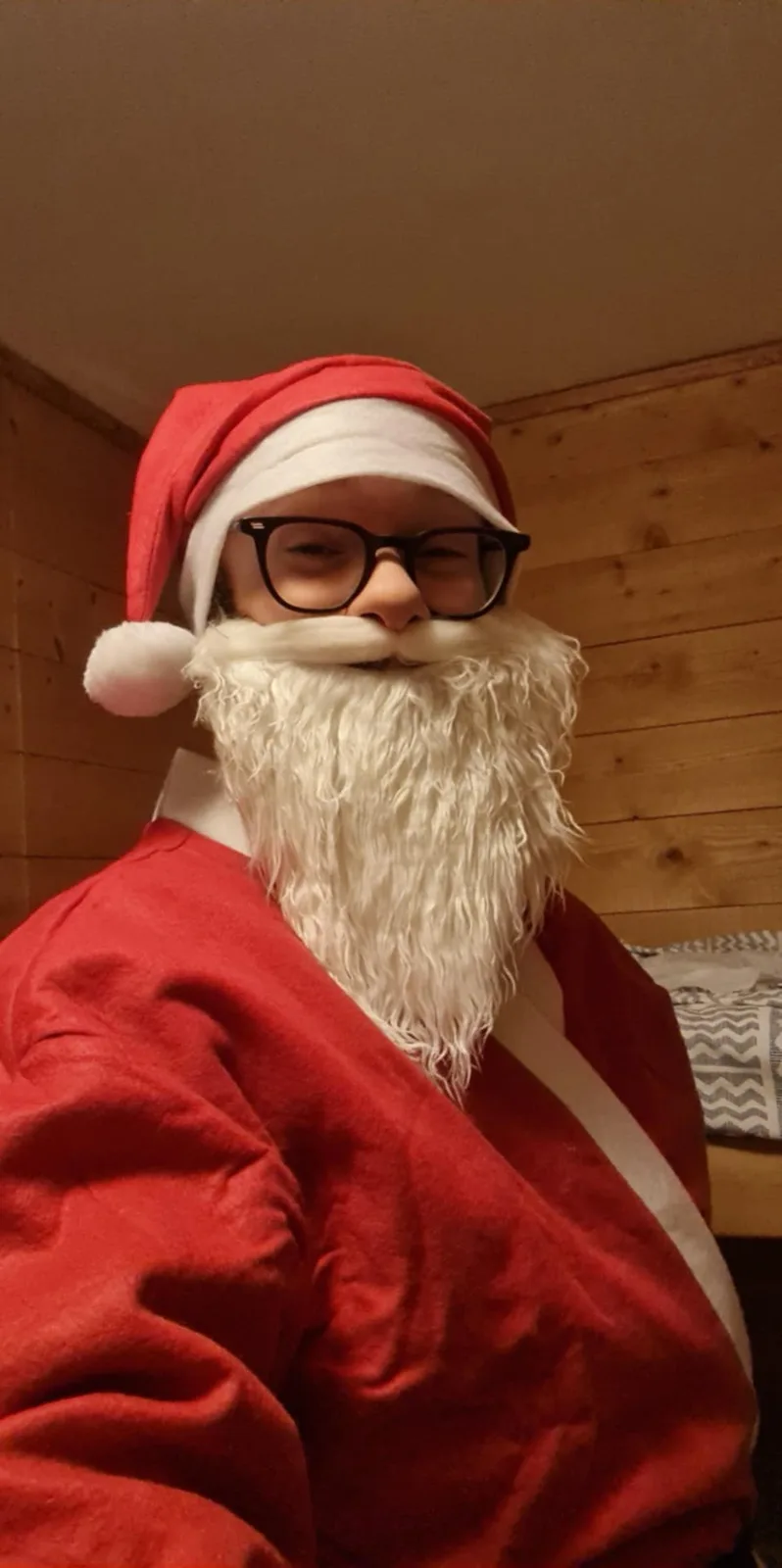 A person wearing a full Santa Claus costume including a red hat with white trim and pom-pom, a red suit with white trim, and…