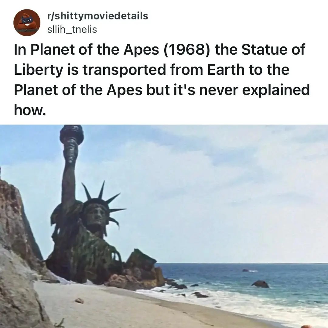 The image shows the Statue of Liberty standing on a rocky beach next to the ocean, appearing weathered and partially broken…