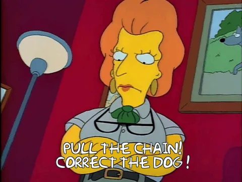 The image shows a cartoon woman with orange hair and a grey uniform, standing in a room with red walls and a framed picture…