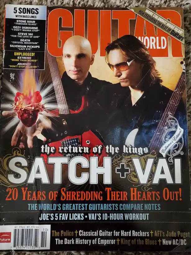 The cover of Guitar World magazine features two guitarists, Joe Satriani and Steve Vai, holding guitars with a flaming heart…