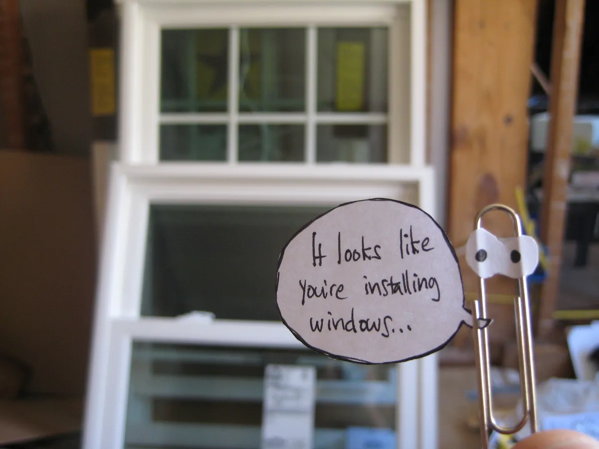 A handmade paperclip character with googly eyes holds a speech bubble that reads 'It looks like you're installing…