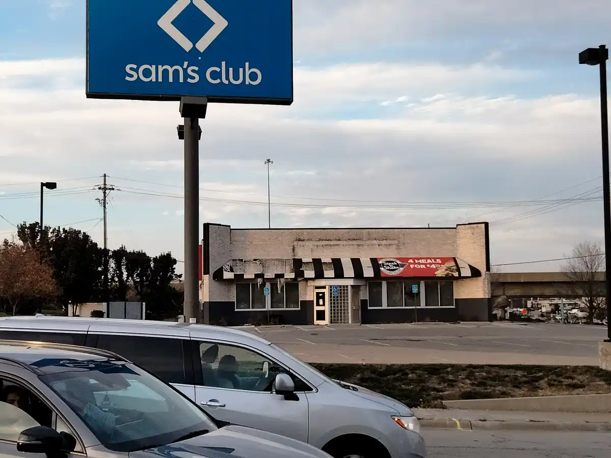 A photo shows a Sam's Club sign towering over a dilapidated, abandoned-looking Steak 'n Shake restaurant with a torn awning…