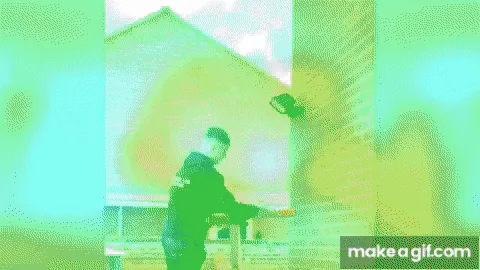 A man in a black hoodie is shown in a sequence of frames working on a brick wall, initially appearing to be painting or…