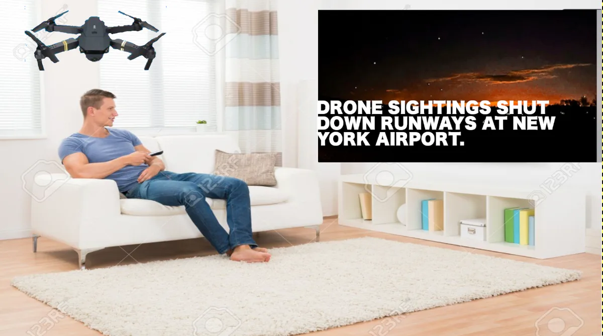 A man sits on a white couch in a living room, holding a remote control, with a black quadcopter drone hovering above him. To…