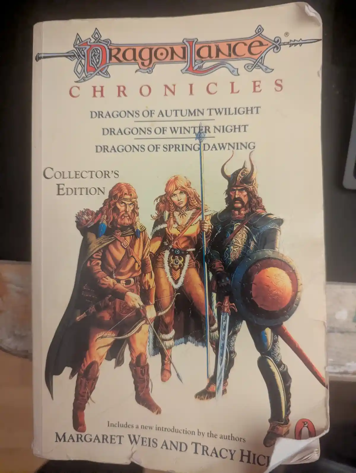 A worn Dragonlance Chronicles Collector's Edition book cover featuring three fantasy adventurers: a bowman, a mage, and a…