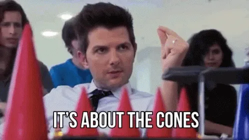 The image shows a man in a white shirt and tie sitting at a table with red party cones in front of him, repeatedly saying…
