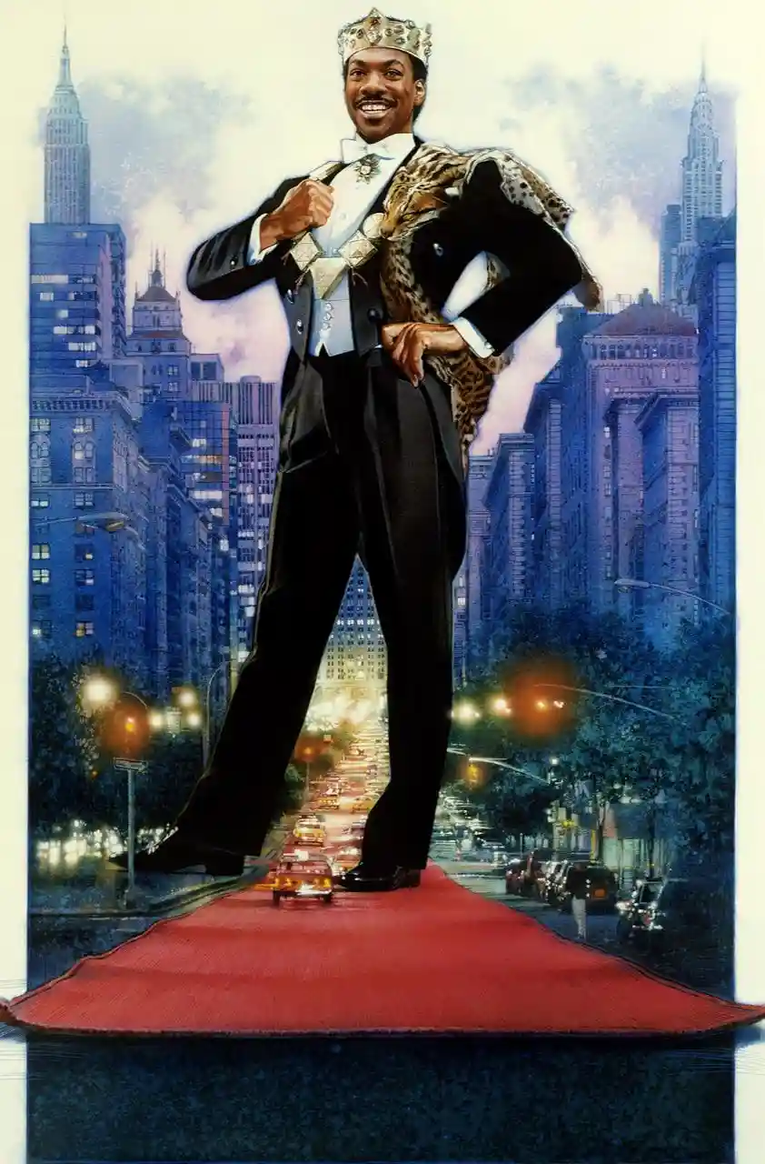 A giant, smiling man wearing a crown, a tuxedo, and a leopard-print cape stands confidently on a red carpet laid over a city…