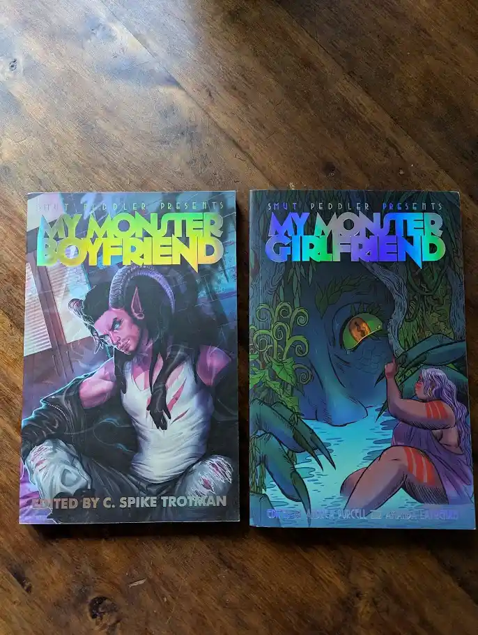 Two comic books titled 'My Monster Boyfriend' and 'My Monster Girlfriend' sit side by side on a wooden surface. The left…
