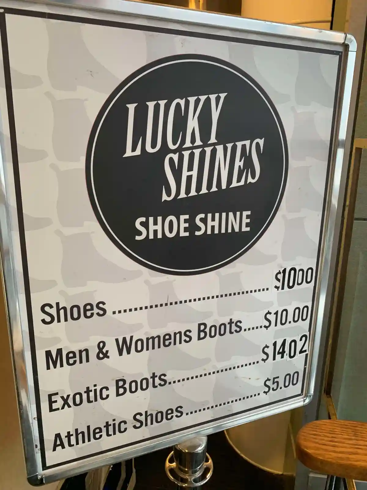 A sign for 'Lucky Shines Shoe Shine' lists absurdly high prices for shoe shining services, including $1000 for regular…