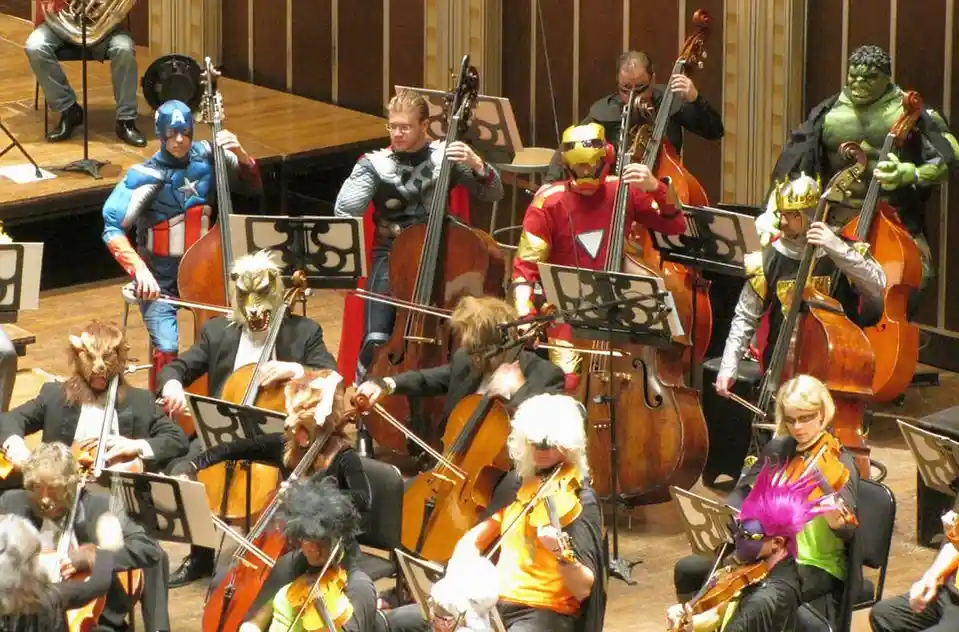 An orchestra of musicians dressed in full costumes of Marvel superheroes like Captain America, Thor, Iron Man, and the Hulk…