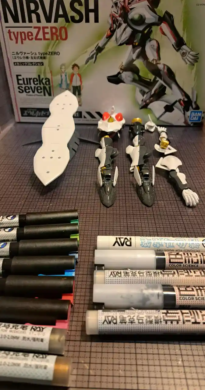 A photo shows unassembled Nirvash typeZERO model kit parts laid out on a grid mat, with two sets of paint markers arranged…