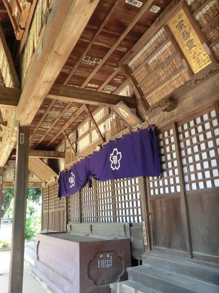a photo of an empty japanese shrine interior with wooden beams, lattice windows, and purple curtains with white cherry…