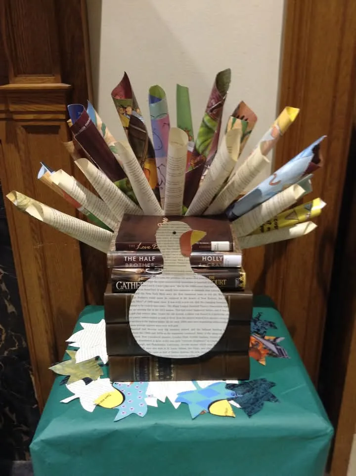 A handmade turkey decoration made from stacked books forming the body, with rolled-up pages creating the tail feathers…