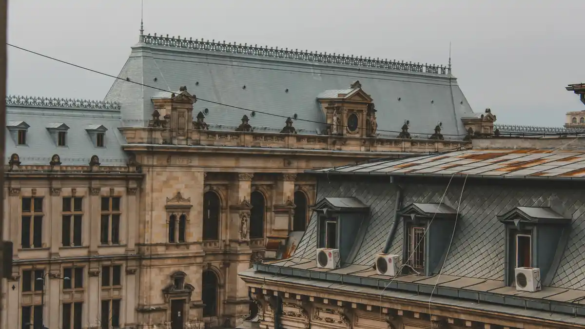 A majestic rooftop panorama unfolds, showcasing intricate stone carvings, ornate balconies, and weathered copper domes. Warm…