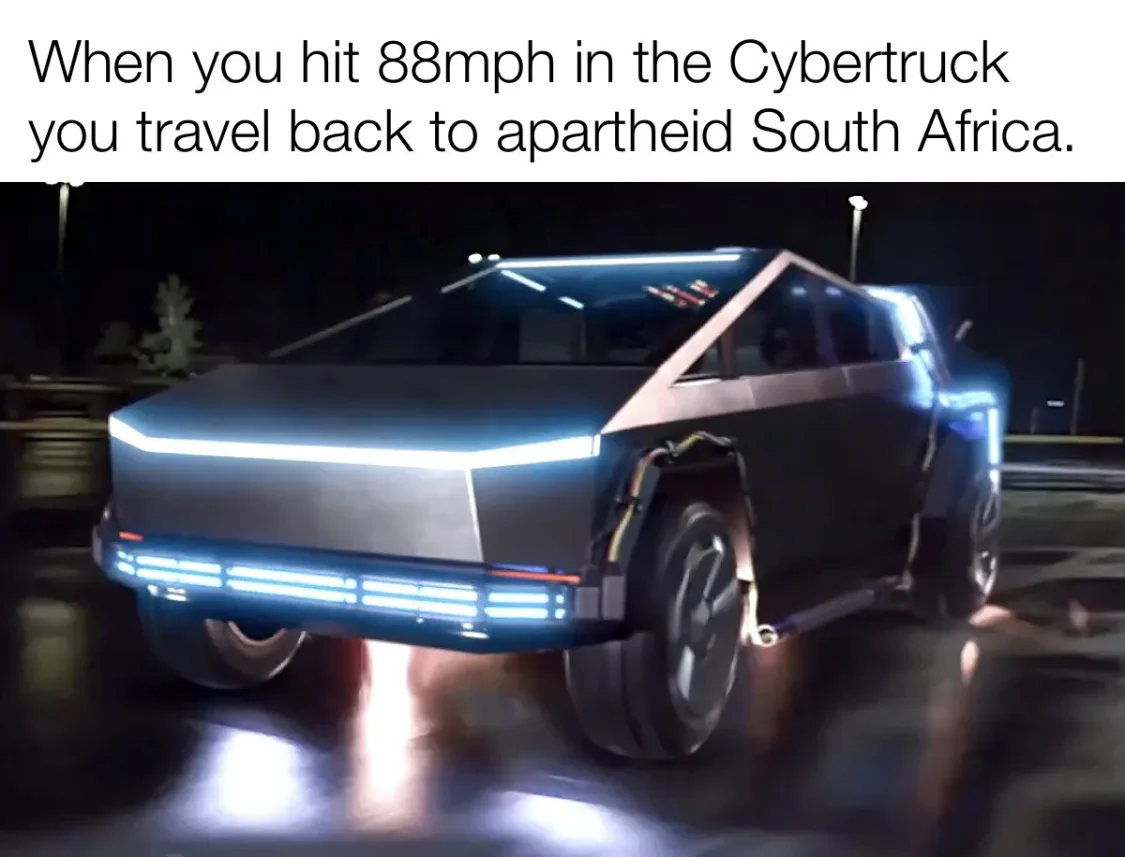A dark, angular Tesla Cybertruck is shown at night, its blue LED lights glowing brightly against a wet, reflective surface…