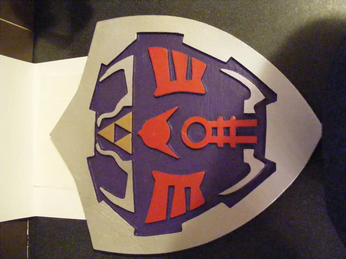 a close-up of a wooden shield with a purple center and silver border, featuring red and gold symbols including the triforce…