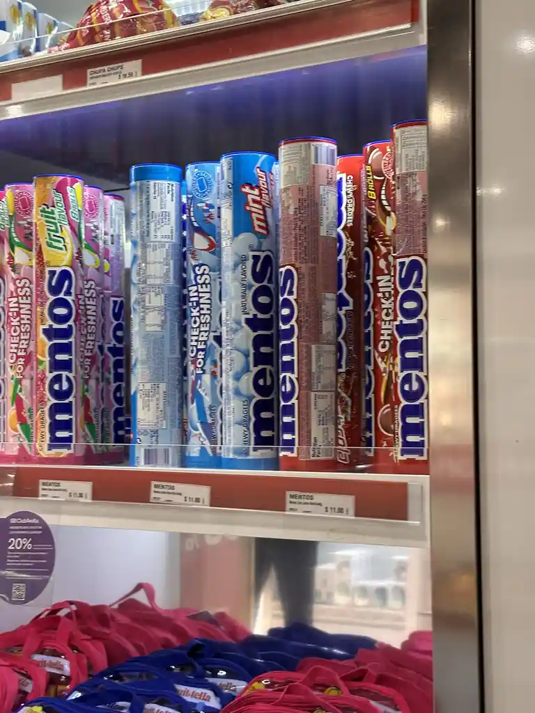 A close-up of Mentos candy tubes arranged vertically on a store shelf, with the text 'CHECK-IN FOR FRESHNESS' visible on the…