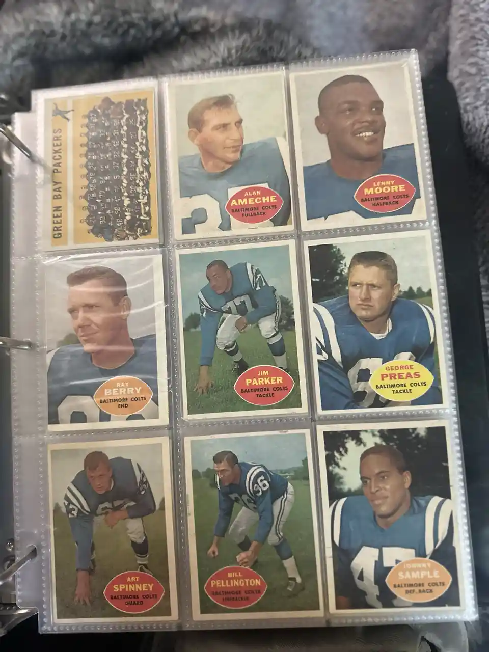 A collection of vintage 1950s-60s Baltimore Colts football trading cards displayed in a binder, featuring players like Alan…