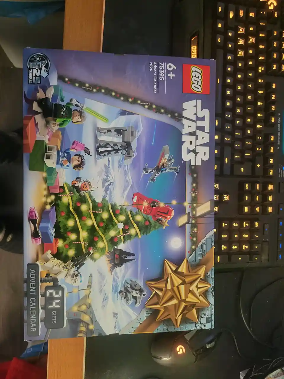 A 2024 LEGO Star Wars Advent Calendar box (set 75395) is shown on a desk next to a gaming keyboard and mouse. The box art…