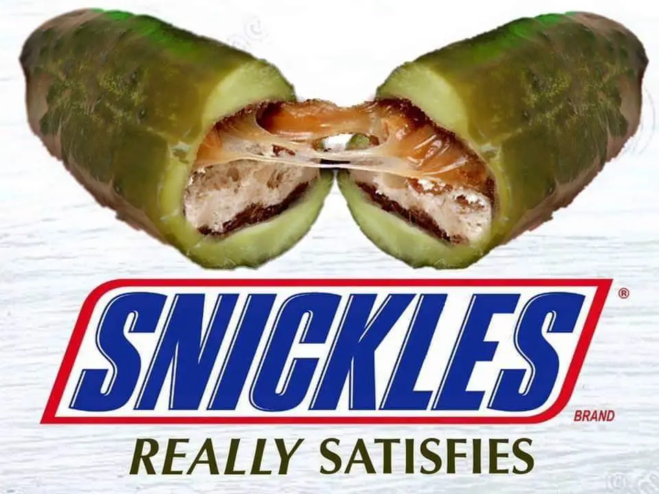 An image shows a pickle cut in half, revealing a gooey, melted cheese and meat filling stretching between the two halves…