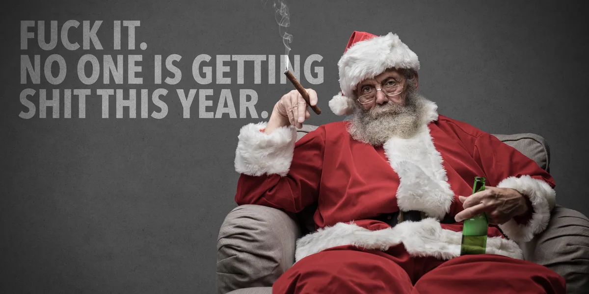 A grizzled, older Santa Claus with glasses and a gray beard sits in a gray armchair, holding a lit cigar in one hand and a…