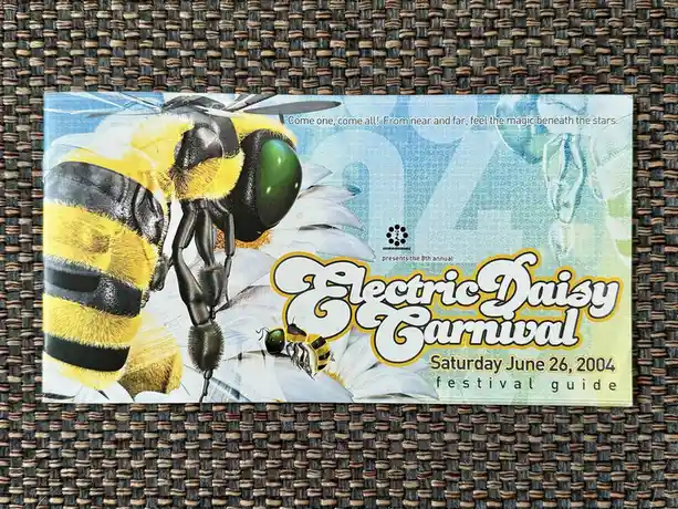 A festival guide for the 8th annual Electric Daisy Carnival on June 26, 2004, features a large, detailed illustration of a…