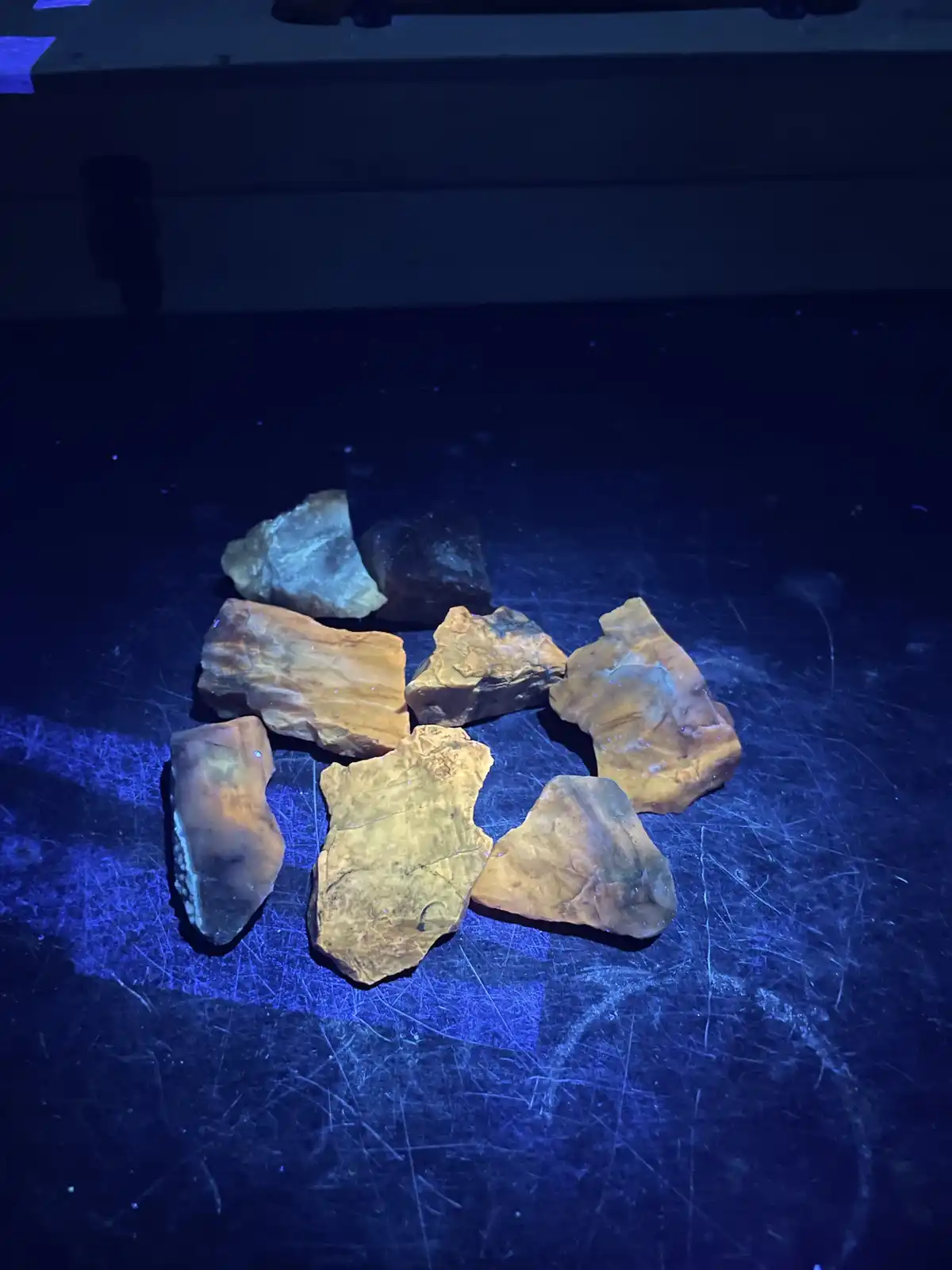 Several irregularly shaped, rough-textured stones with earthy tones of brown, tan, and gray are scattered on a scratched…