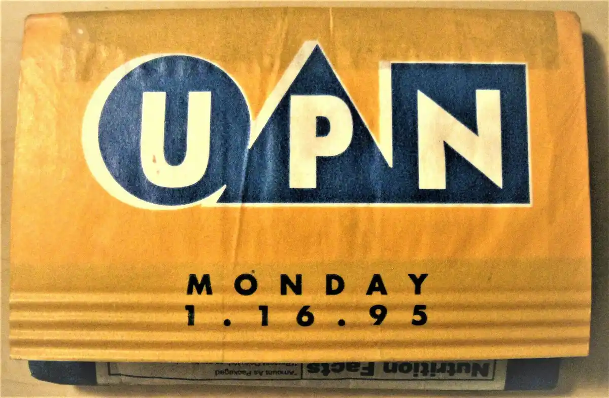 A close-up of a yellow cardboard box, likely a snack or cereal package, with the UPN TV network logo prominently displayed…