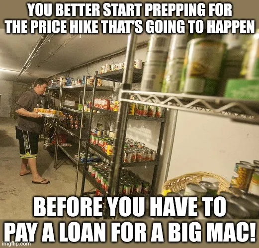 A man in a basement pantry stands holding a tray of canned goods, surrounded by metal shelves overflowing with food items…