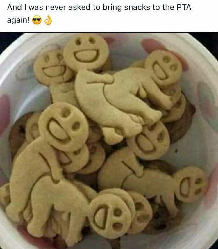 A white bowl filled with light-brown sugar cookies shaped like smiling faces and baby figures, some with exaggerated grins…