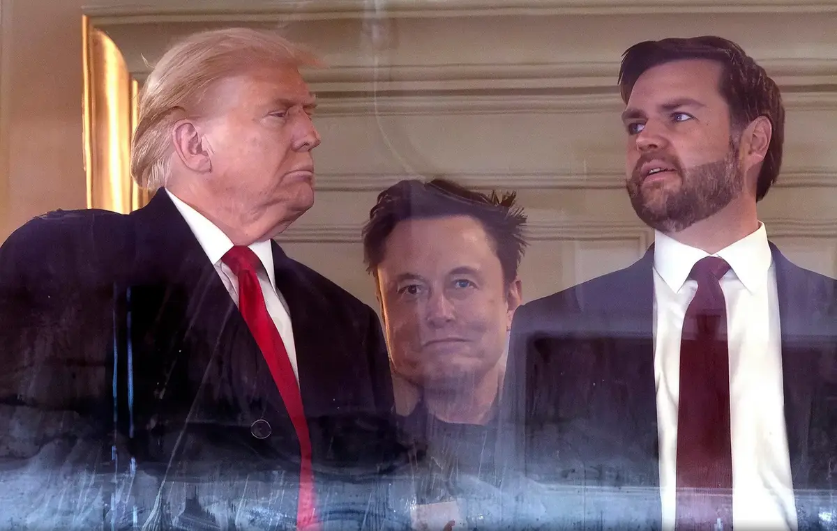 The image shows three men in suits: Donald Trump on the left with a red tie, Elon Musk in the center looking forward, and…