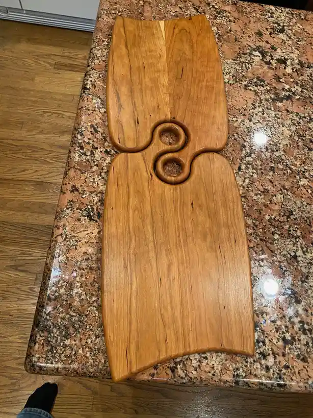 A wooden object with a distinctive curved shape and two circular cutouts sits on a speckled granite countertop, resembling a…