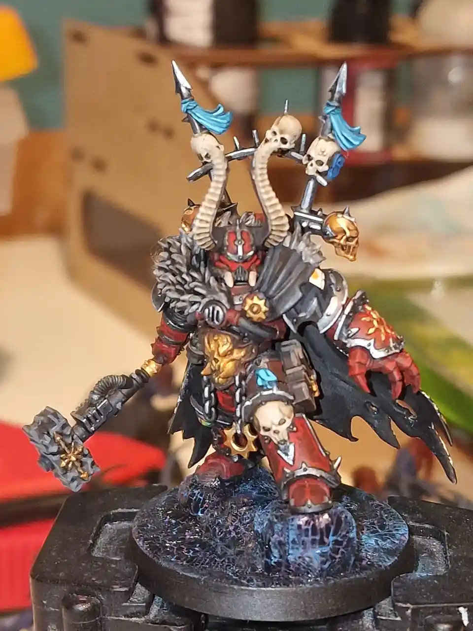 A highly detailed, painted miniature of a grim reaper-like warrior with skulls, horns, and ornate armor stands on a cracked…