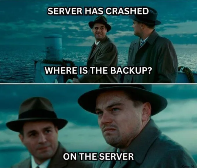 Two men in fedoras on a boat at sea. Top panel: one man smiles while the other asks, 'WHERE IS THE BACKUP?'. Bottom panel…