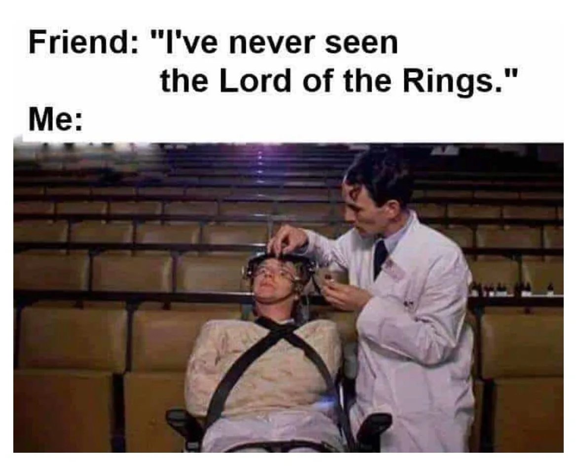 A person in a white lab coat is adjusting a headpiece on another person strapped into a chair in an empty auditorium. The…