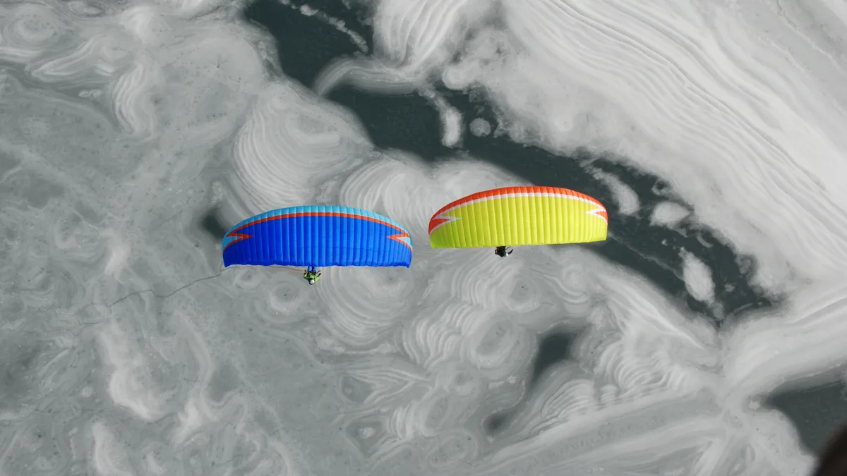 Over Austria's frozen Tyrolean Sea, bundled-up paraglider pilots harness winter winds, expertly navigating specially…