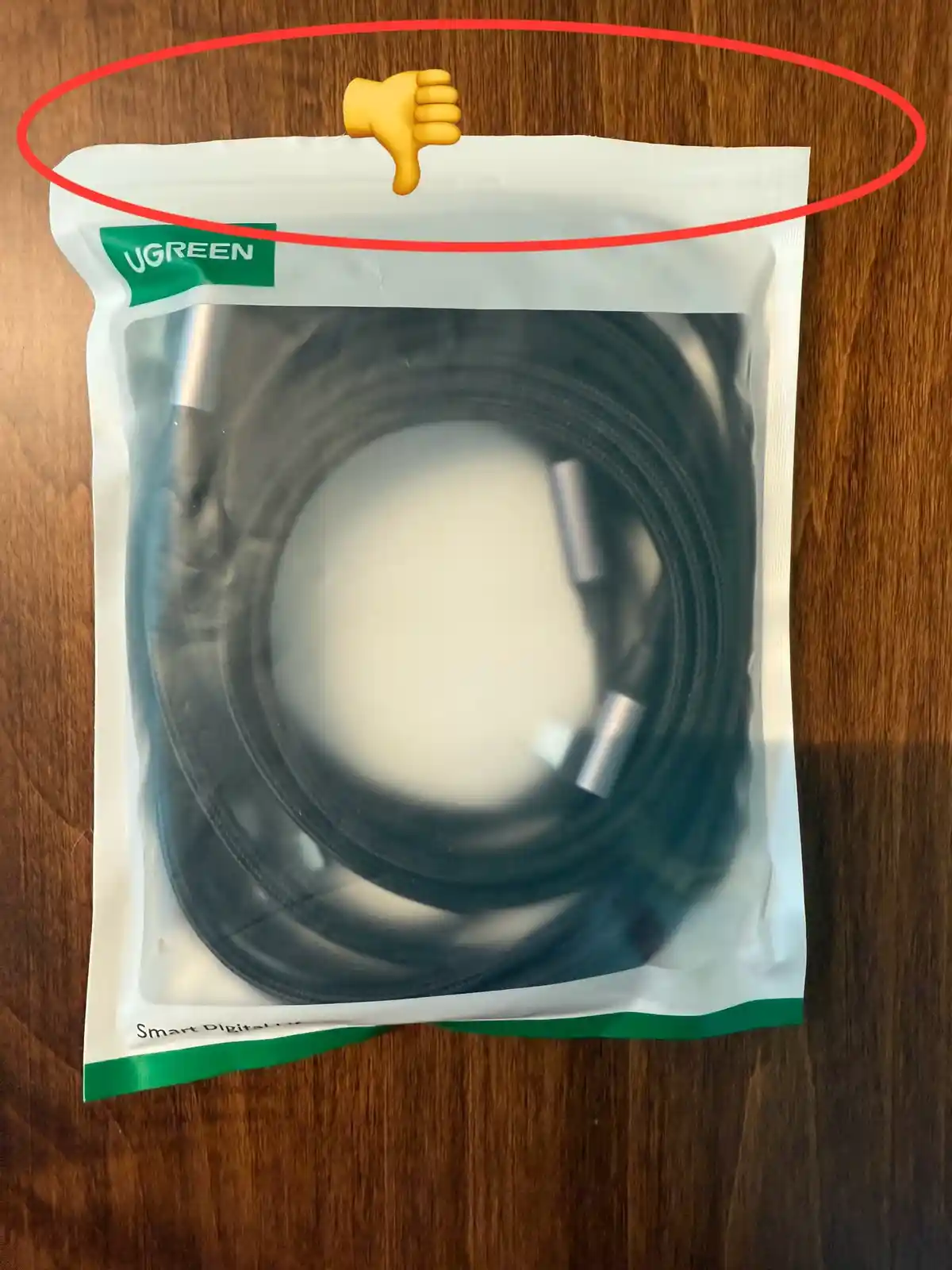 A UGREEN-branded cable in a clear plastic package sits on a wooden surface. A red circle highlights the top edge of the…
