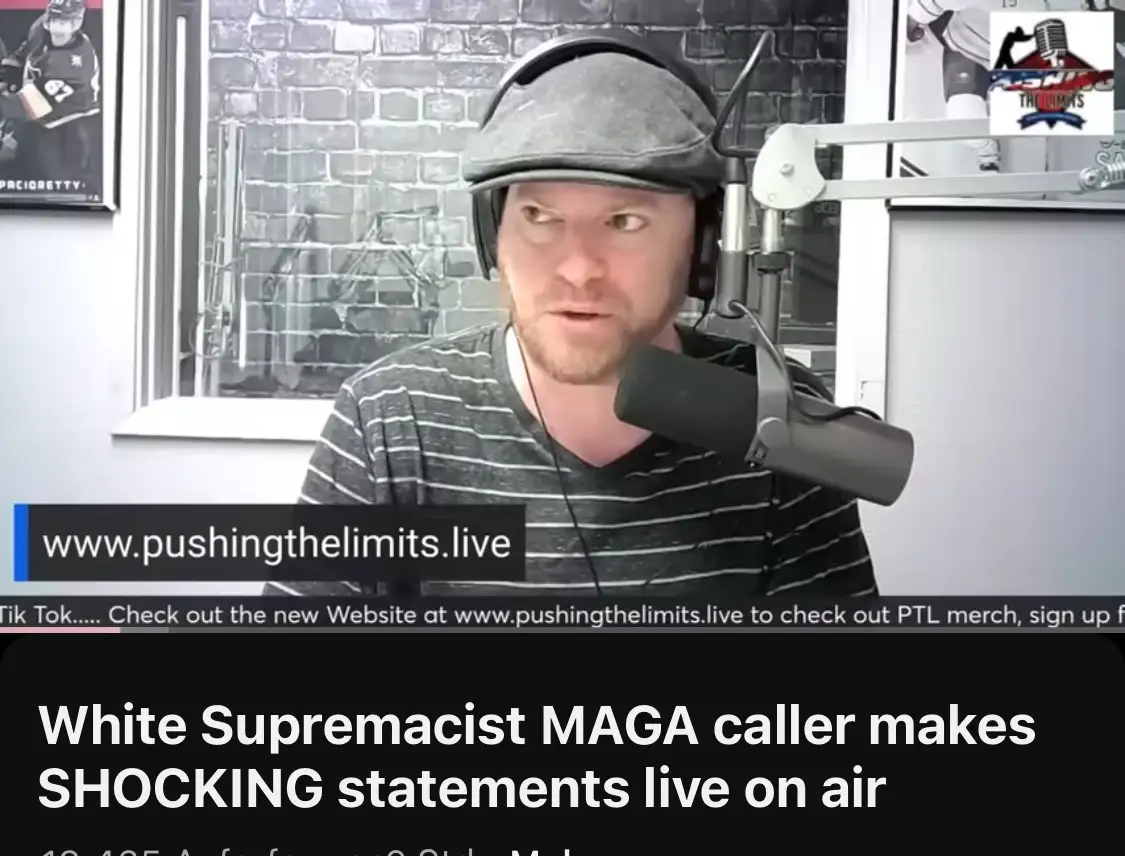 A man with a beard, wearing a grey flat cap and headphones, sits in front of a microphone in a studio with a brick wall…