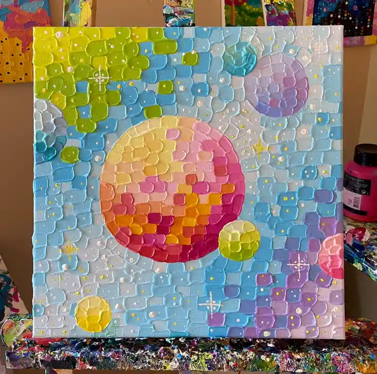 A textured, colorful painting on canvas depicts a large, smiling planet with a gradient of pink, orange, and yellow hues…