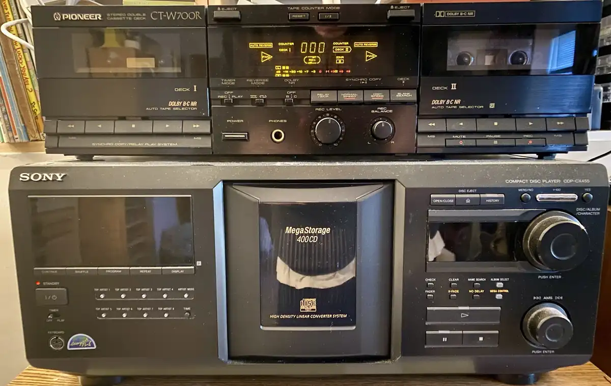 A photo of a vintage Sony CD player with a CD labeled 'MegaStorage 400CD' inserted, sitting below a Pioneer double cassette…