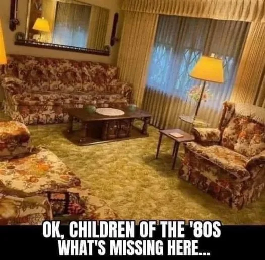 A vintage 1980s living room with floral-patterned couches, chairs, and ottoman, a wooden coffee table, a floor lamp, and…