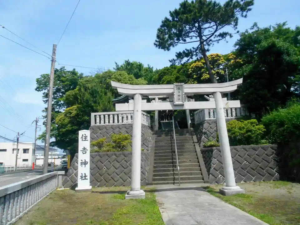 A photograph of the entrance to a Japanese Shinto shrine, featuring a large stone torii gate with the characters '住吉神社'…